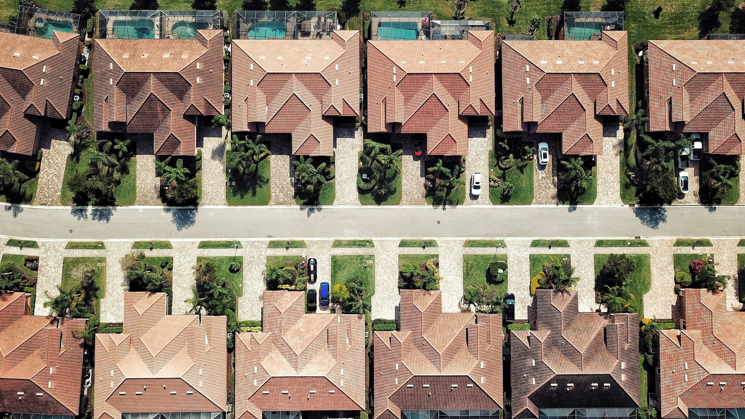 Vista aérea de un barrio de Florida con techos de tejas, jaulas para piscinas y jardines con palmeras